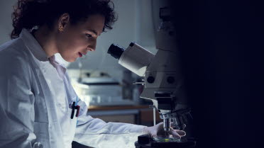 Woman in laboratory looking into a microscope