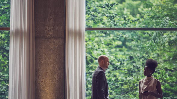 Eine Frau und ein Mann stehen sich an einem Fenster gegenüber
