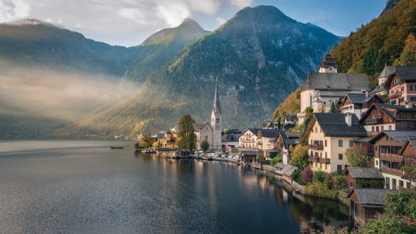 Kleine Ortschaft an einem See mit Bergen im Hintergrund