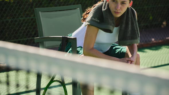 Sitzende Frau auf dem Tennisplatz