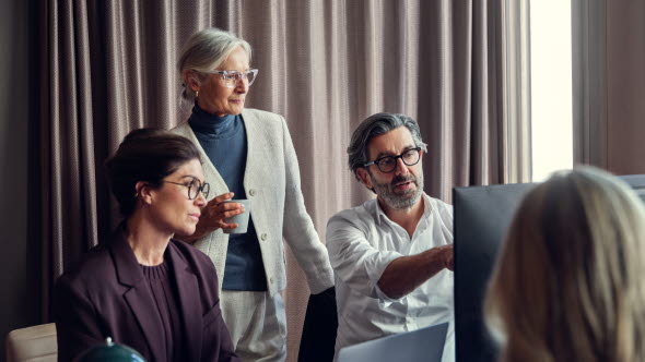 Mehrere Personen sitzen vor einem PC