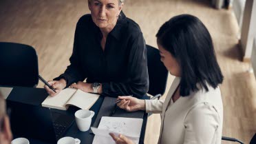 Zwei Frauen sitzen am Tisch und sind im Gespräch